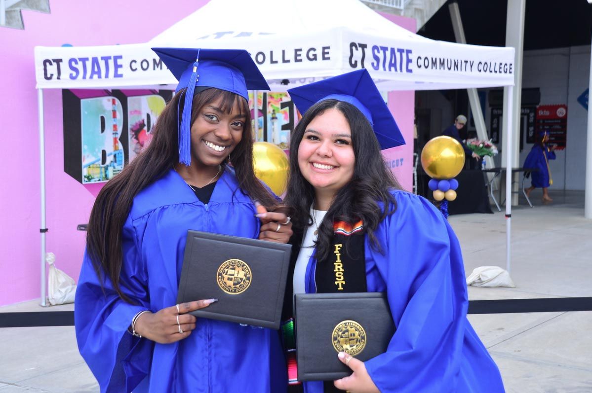 Students posing with degrees in hand